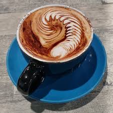 Latte art in a black cup on a blue saucer