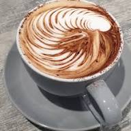 Small latte with latte art on a grey saucer